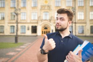 a man holding books and giving a thumbs up