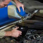 Mechanic pouring oil into car engine